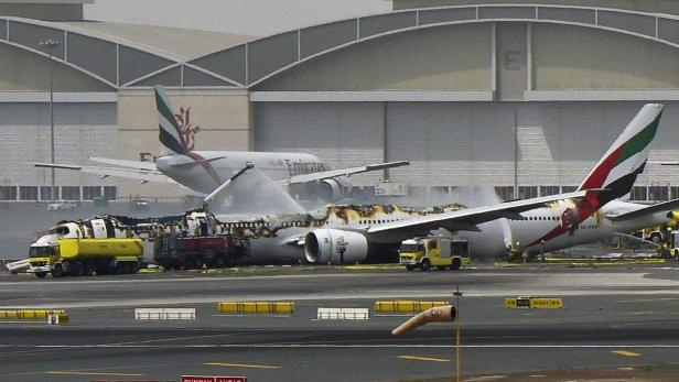 Ein beschädigtes Flugzeug der Fluggesellschaft Emirates steht auf einem Rollfeld, umgeben von Feuerwehrfahrzeugen.