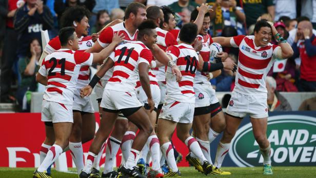 Japanische Rugbyspieler feiern gemeinsam auf dem Spielfeld.
