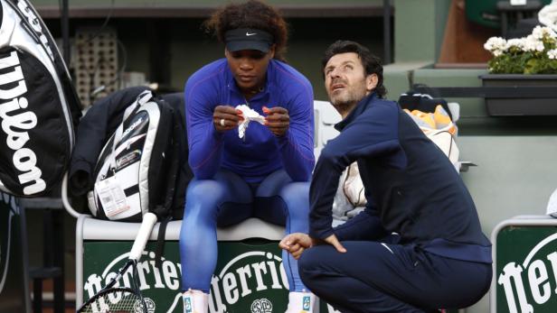 Serena Williams sitzt mit ihrem Trainer auf der Bank während eines Tennismatches.