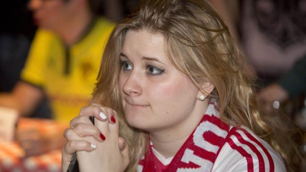 Eine junge Frau mit einem rot-weißen Schal blickt angespannt zur Seite.