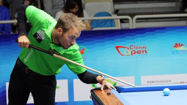 Ein Billardspieler zielt auf eine Kugel beim China Open.