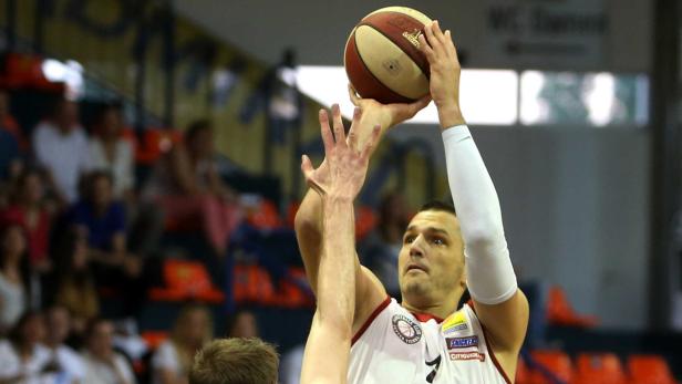 Ein Basketballspieler wirft den Ball, während ein anderer Spieler versucht, ihn zu blocken.