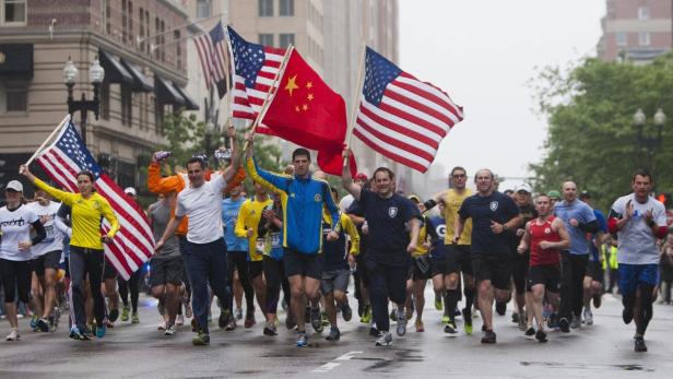 Eine Gruppe von Läufern hält amerikanische und chinesische Flaggen bei einem Marathonlauf.