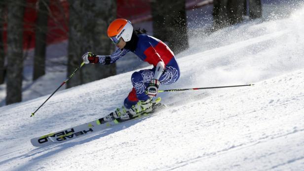 Eine Skifahrerin fährt einen schneebedeckten Hang hinunter.