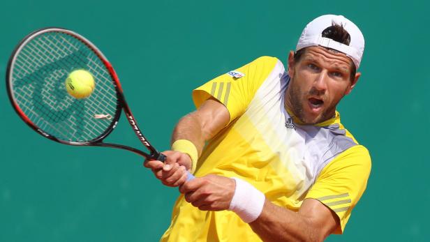 Ein Tennisspieler schlägt einen gelben Tennisball mit seinem Schläger.