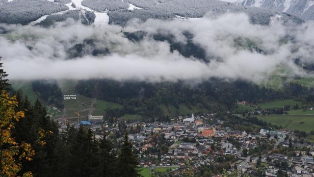 Blick auf eine Stadt in den Bergen unterhalb einer Wolkendecke.