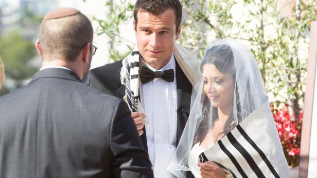 Ein jüdisches Brautpaar steht unter einer Chuppa bei ihrer Hochzeit.