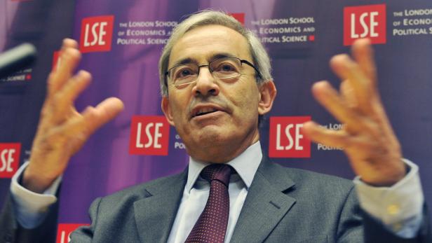 Ein Mann mit Brille gestikuliert vor dem Hintergrund der London School of Economics.