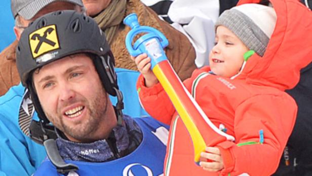 Ein Mann mit Skihelm und ein Kind mit einer Spielzeugtrompete.