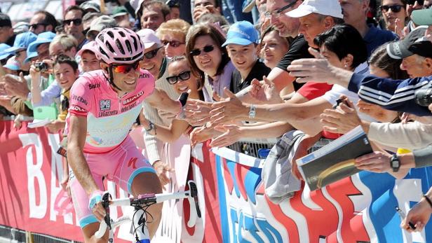 Ein Radrennfahrer im rosa Trikot fährt an einer jubelnden Menschenmenge vorbei.