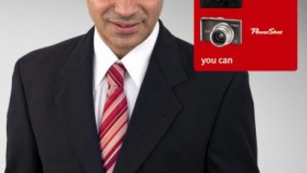 Ein Mann im Anzug und Hut hält Geldscheine in der Hand, daneben Werbung für Canon-Kameras.