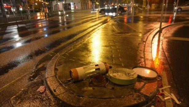 Ein offener Kabelschacht liegt auf einer nassen Straße.