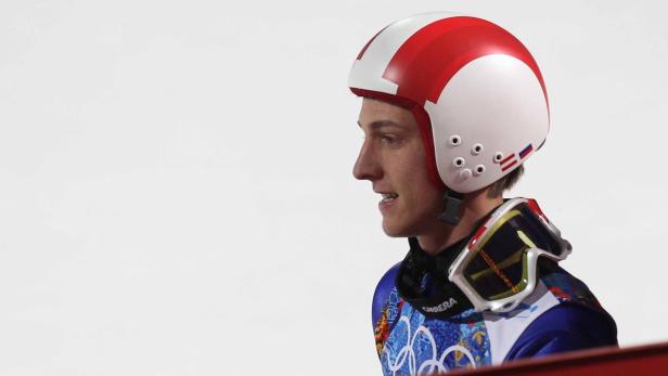 Ein Skispringer mit rotem und weißem Helm blickt nach links.