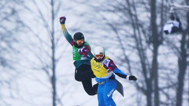 Zwei Snowboarder springen vor einem verschneiten Hintergrund.