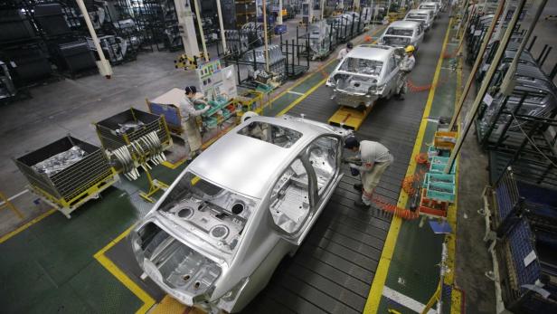 In einer Fabrik arbeiten Arbeiter an der Montage von Autokarosserien.