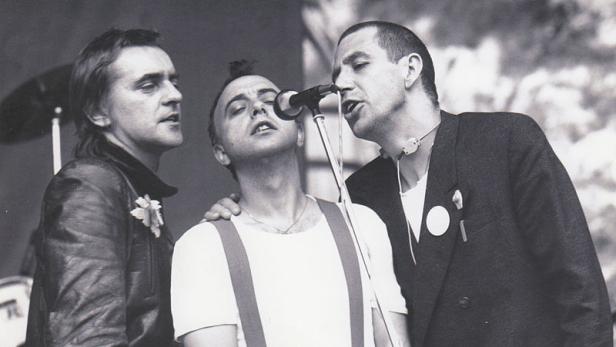 Drei Männer singen gemeinsam in ein Mikrofon.