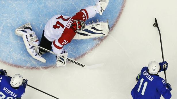 Ein Eishockeytorwart wehrt einen Schuss von Anže Kopitar ab, während ein weiterer Spieler zusieht.