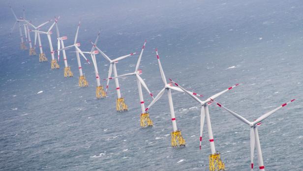 Eine Reihe von Windkraftanlagen steht im Meer.