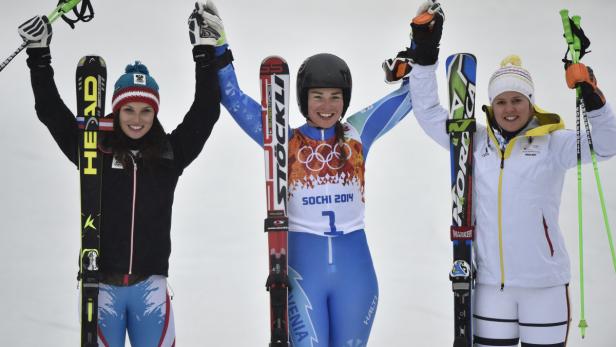 Drei Skirennläuferinnen feiern mit erhobenen Armen ihren Erfolg.