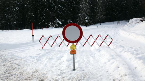 Ein rot-weißes Verbotsschild steht auf einer schneebedeckten Straße.