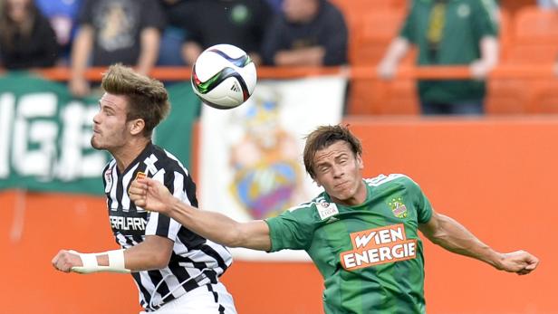 Zwei Fußballspieler kämpfen um den Ball während eines Spiels.