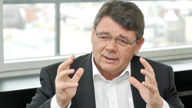 Ein Mann mit Brille und Anzug gestikuliert mit den Händen.