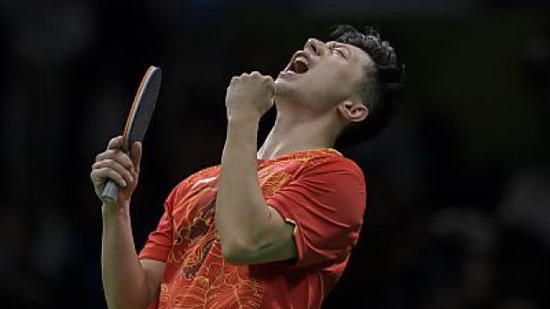 Ein Tischtennisspieler in rotem Trikot jubelt mit erhobener Faust und Schläger.