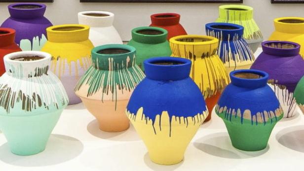 Eine Sammlung von bunten, bemalten Töpfen steht auf einem Tisch.