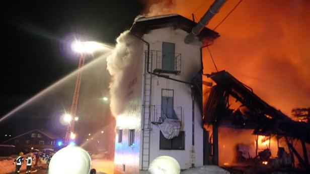 Ein Gebäude steht in Flammen und wird von Feuerwehrleuten gelöscht.