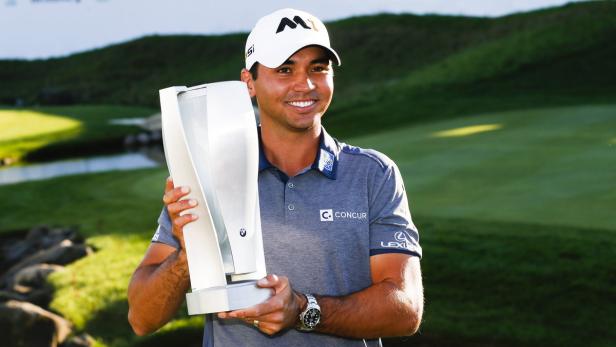 Ein lächelnder Mann im Golfoutfit hält eine silberne Trophäe in den Händen.