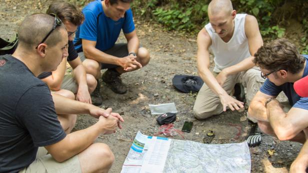 Survival-Trainer Georg Brzobohaty übt mit den Abenteurern das Orientieren mit Karte und Bussole.