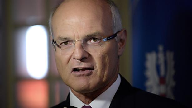 Ein Mann mit Brille und Anzug spricht in ein Mikrofon.