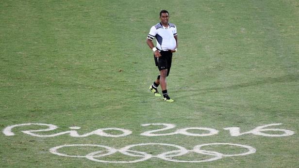 Ein Rugby-Spieler steht auf einem Rasen mit dem Schriftzug „Rio 2016“ und den olympischen Ringen.