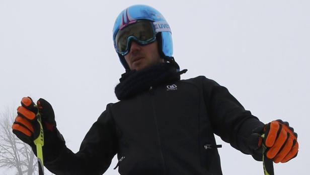 Ein Skifahrer mit Helm und Skibrille hält Skistöcke.