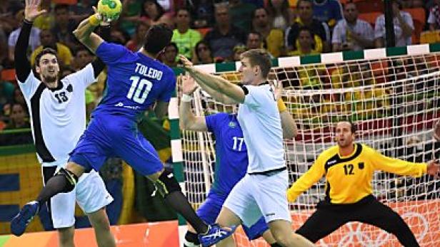 Ein Handballspieler wirft den Ball auf das Tor, während der Torwart versucht, ihn abzuwehren.