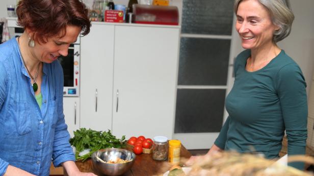 Zwei Frauen bereiten gemeinsam eine Mahlzeit in einer Küche zu.