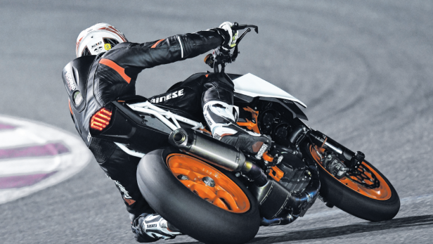 Ein Motorradfahrer in Lederkombi fährt eine Kurve auf einer Rennstrecke.