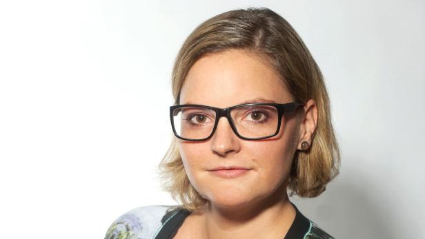 Eine Frau mit blonden Haaren und Brille blickt in die Kamera.