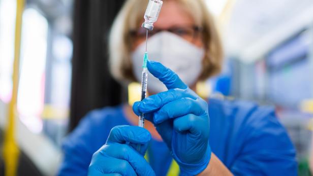 Medizinisches Personal zieht eine Spritze mit einem Impfstoff gegen das Corona-Virus auf