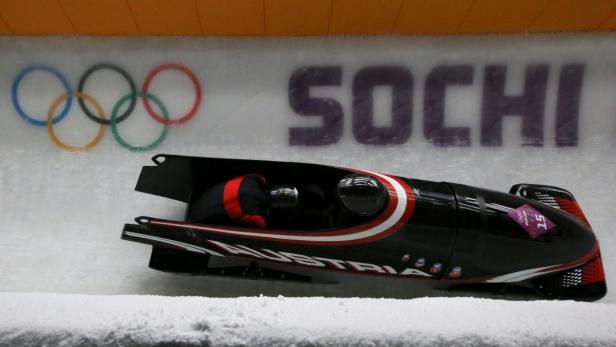 Ein Bobschlitten mit der Aufschrift „Austria“ rast auf einer Eisbahn in Sotschi.