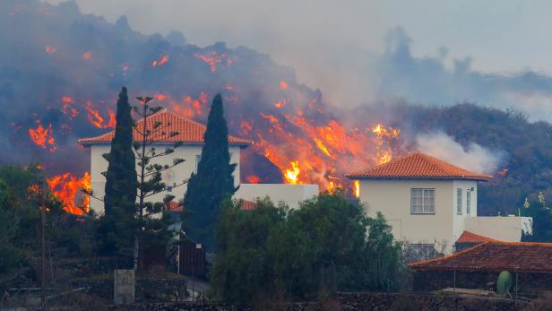 Lava flows behind a house following the eruption of a volcano in Spain