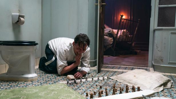 Oliver Masucci als Anwalt, der in einem Hotelzimmer in Einzelhaft genommen wird und mit Schachspielen beginnt: „Schachnovelle“