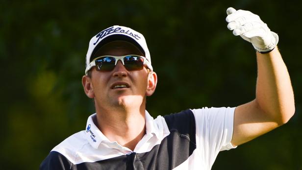 Ein Golfspieler mit Sonnenbrille und Kappe hebt die Hand mit einem Golfhandschuh.