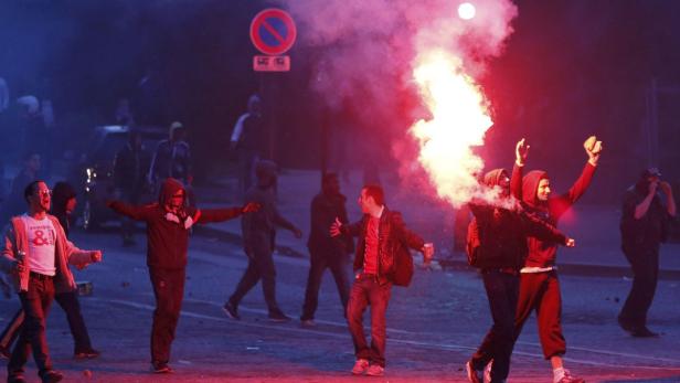 Eine Gruppe von Demonstranten zündet Rauchbomben auf einer Straße an.