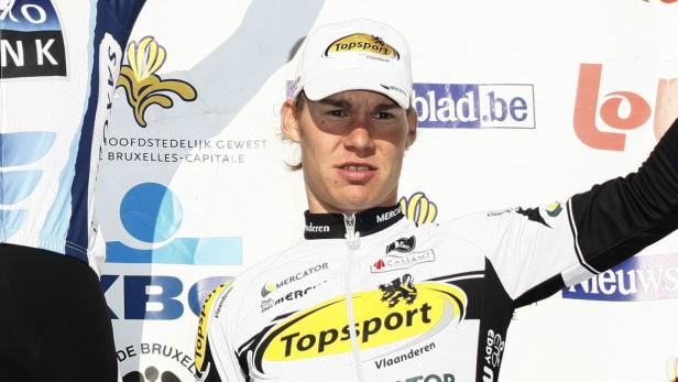 Ein Radrennfahrer im Trikot des Teams Topsport Vlaanderen steht auf einem Podium.