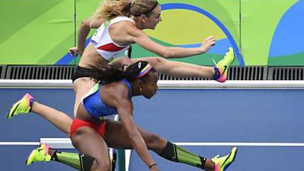 Zwei Hürdenläuferinnen springen über die Hürden auf einer Leichtathletikbahn.