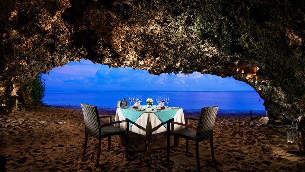 Ein romantisches Abendessen in einer Höhle am Strand mit Blick auf das Meer.