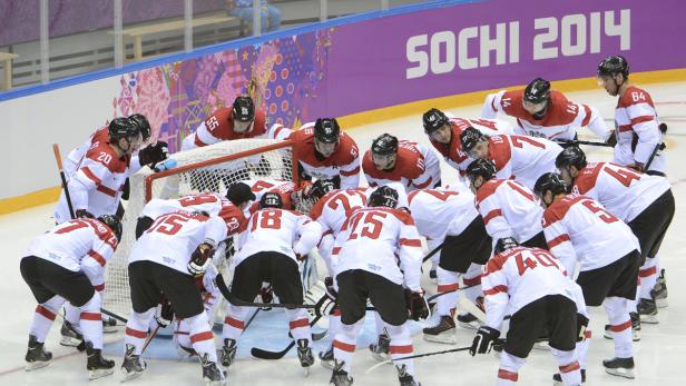 Österreichische Hockeyspieler umringen den Torwart während eines Spiels in Sotschi 2014.