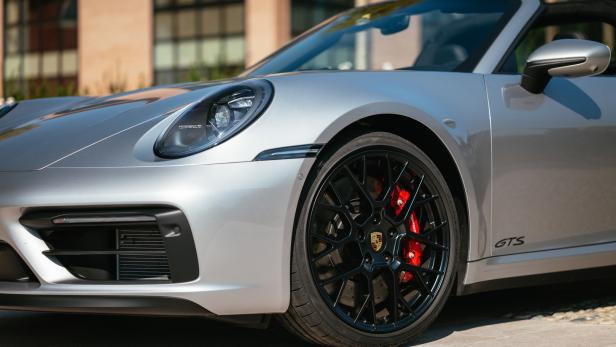 Detailansicht eines silbernen Porsche 911 GTS mit schwarzen Felgen und roten Bremssätteln.
