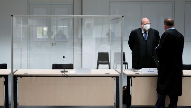 Two lawmakers stand next to the empty seat of the accused 96-year-old former secretary to the SS commander of the Stutthof concentration camp before a trial against her, in Itzehoe